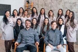 Foto de grupo da equipe da Barini Odontologia, todos vestindo jalecos cinza